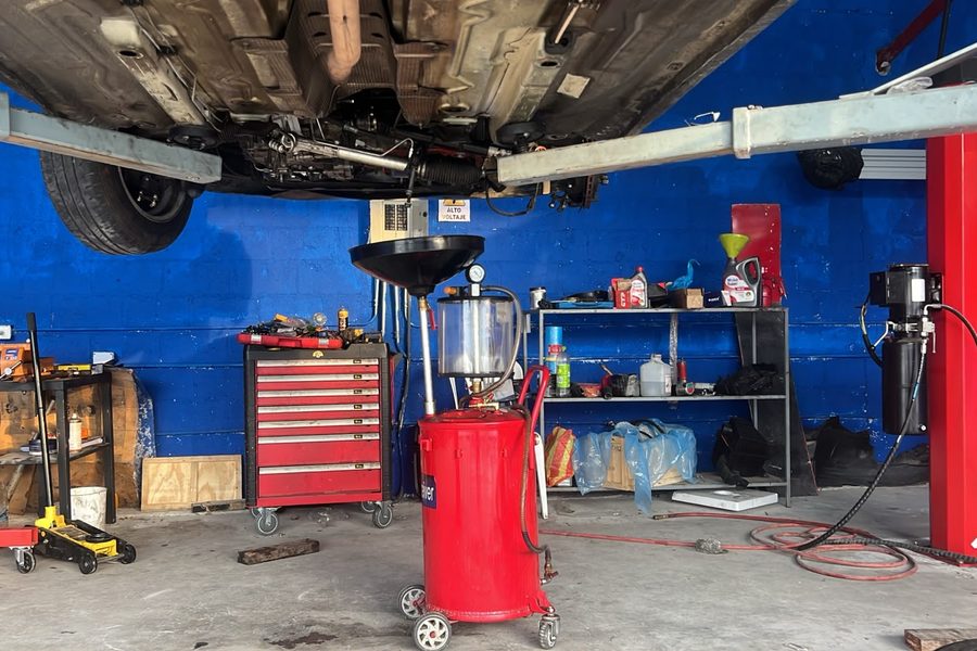 Extractor de aceite bajo un vehículo elevado en el taller